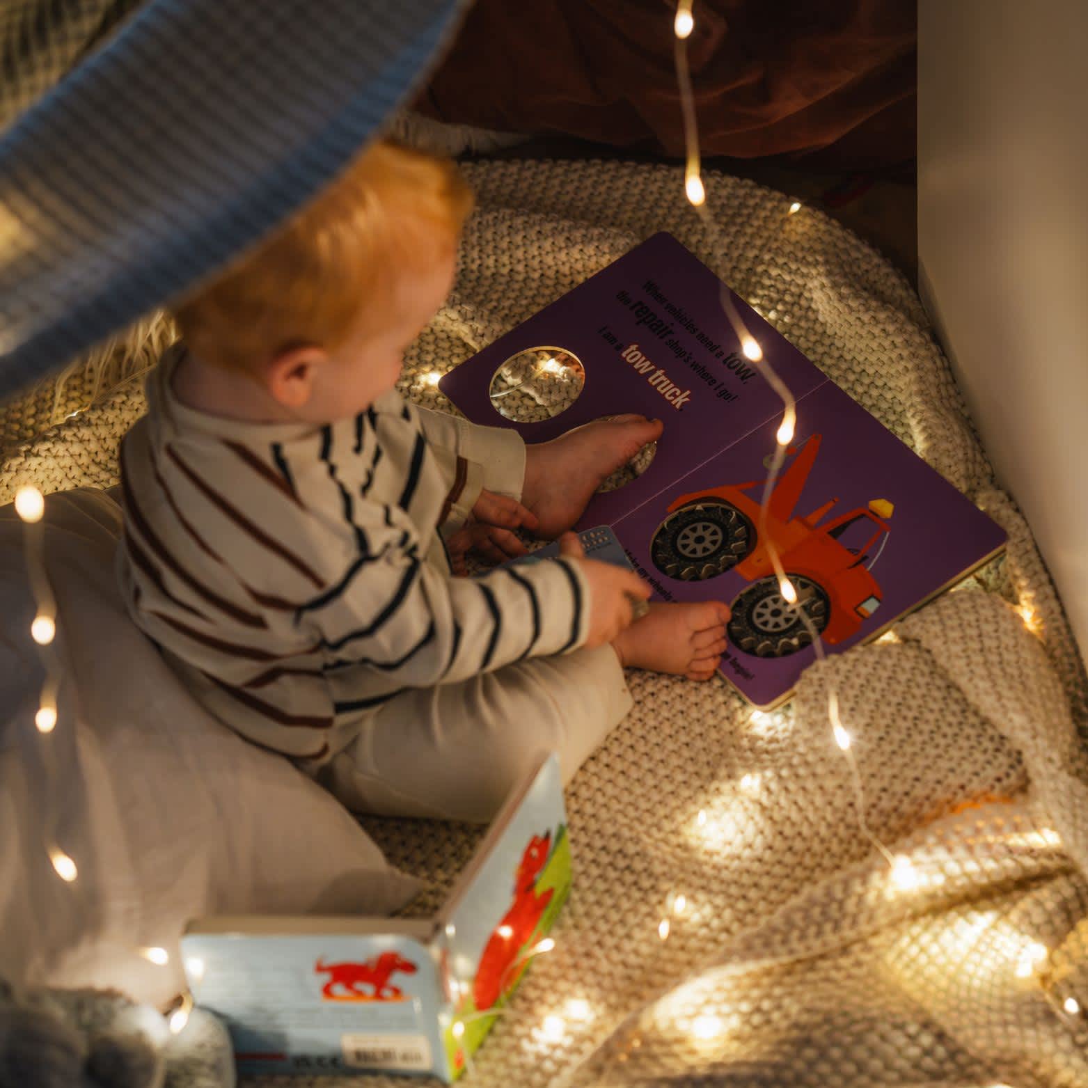 Child reading in a pillow fort with the solar string light.