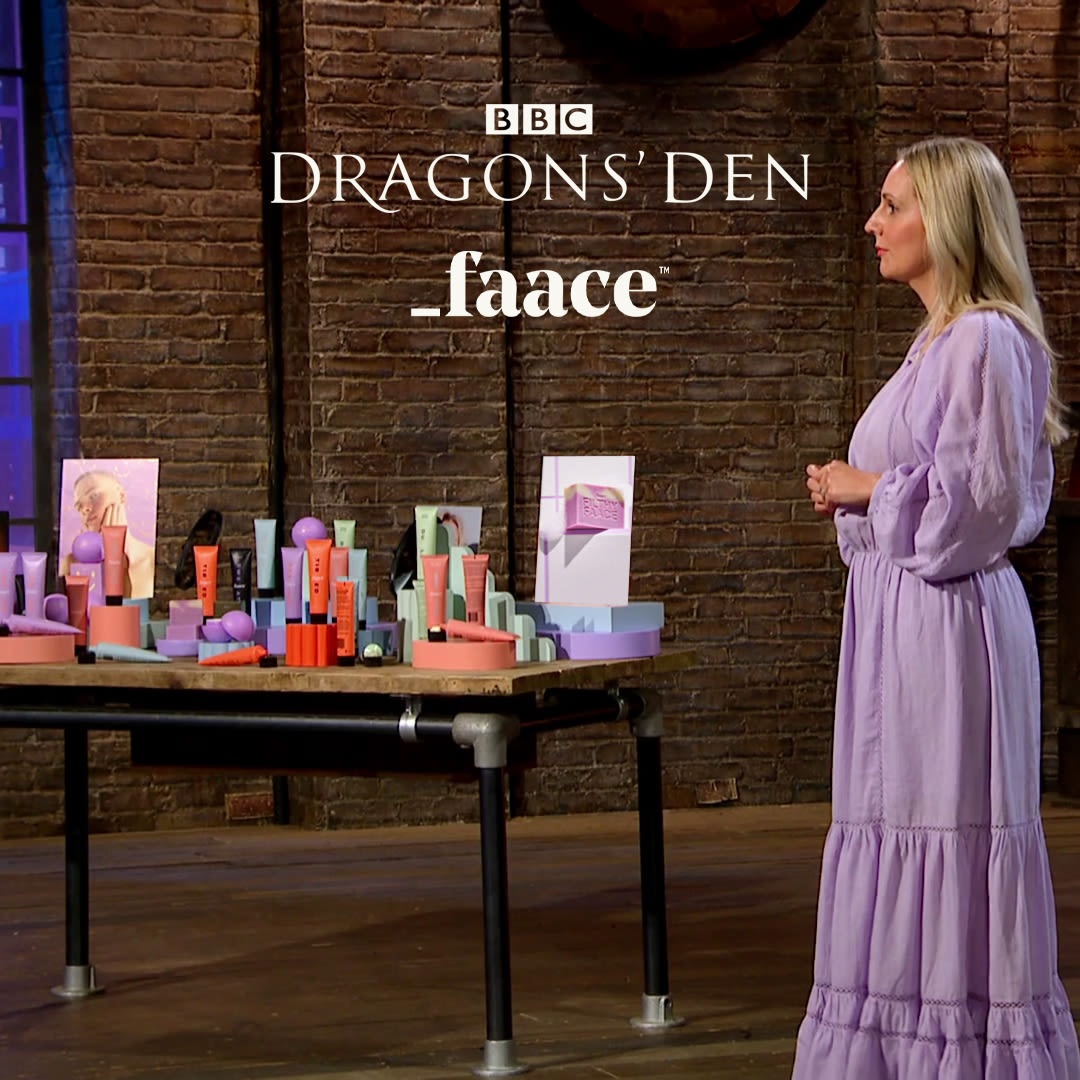 Woman standing beside a display of colorful cosmetic products on a table in Dragons' Den.