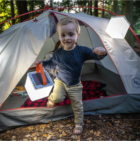 Child jumping out of a tent with LuminAID lanterns