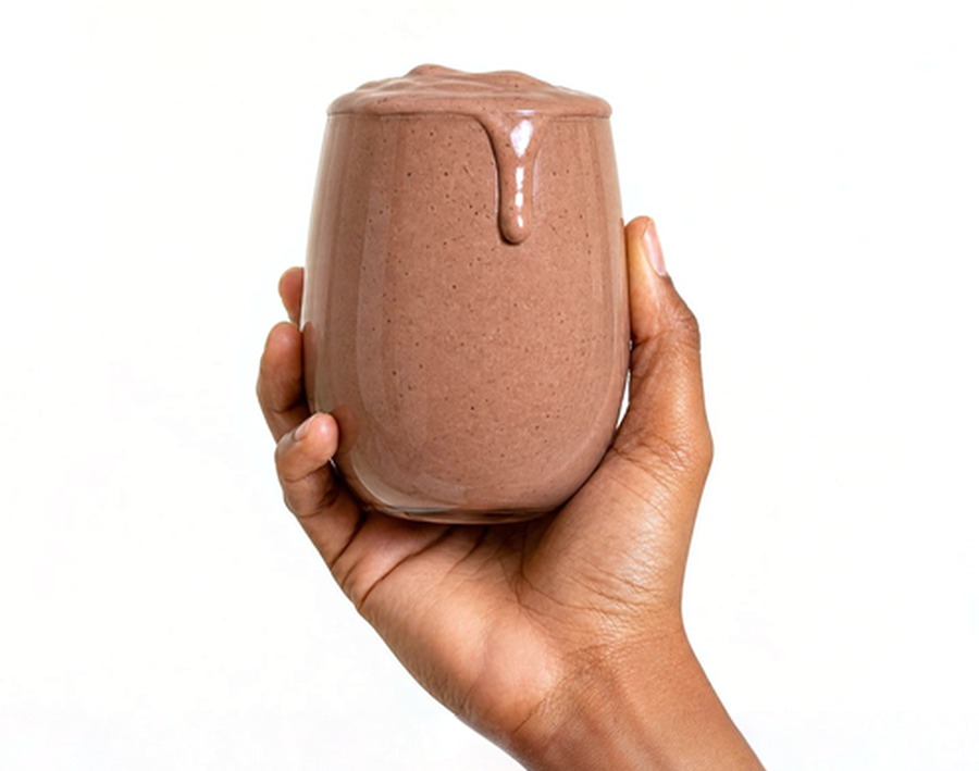A hand holding a glass of chocolate LyfeFuel Essentials Shake