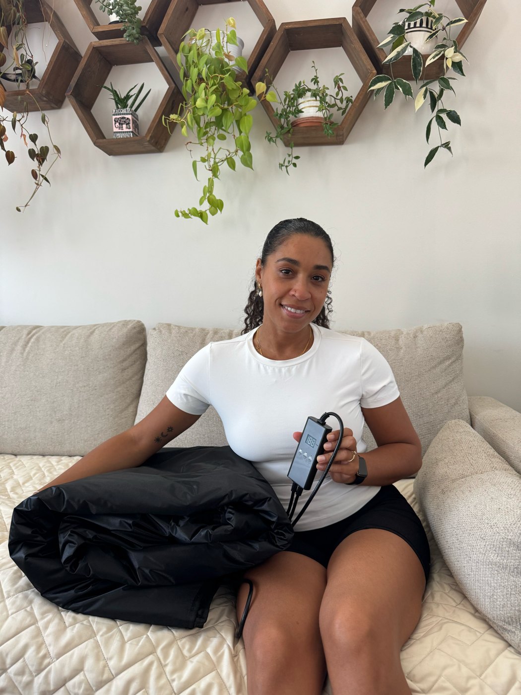 Woman on her sofa with the FlexiHeat sauna blanket and handheld controller
