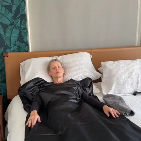 Woman relaxing in bed inside the FlexiHeat sauna blanket