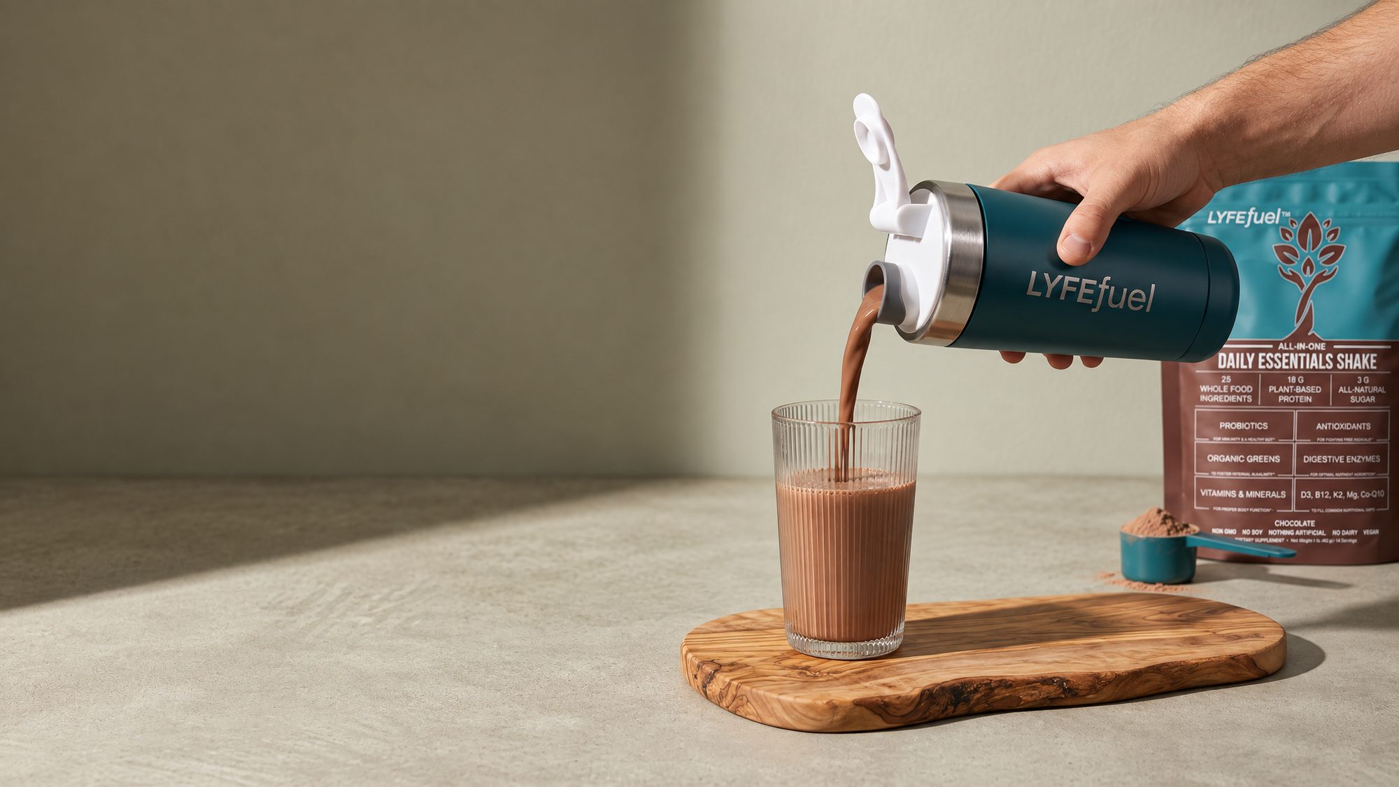 LyfeFuel Daily Essentials Shake poured thin from the LyfeFuel shaker into a glass, next to the Chocolate bag